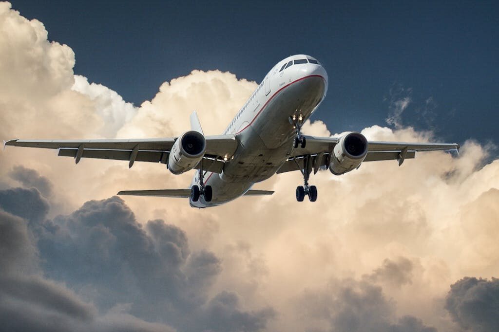 White and Red Plane Beside Clouds Low-angle Photography